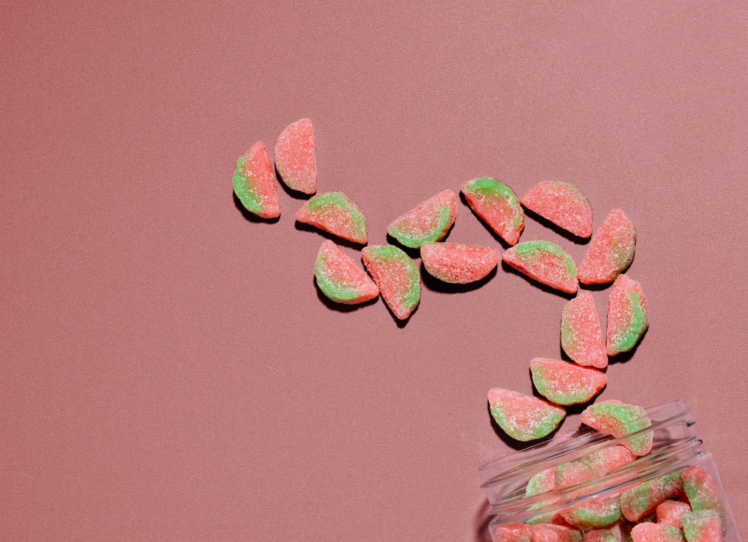 a jar of candy on a pink surface