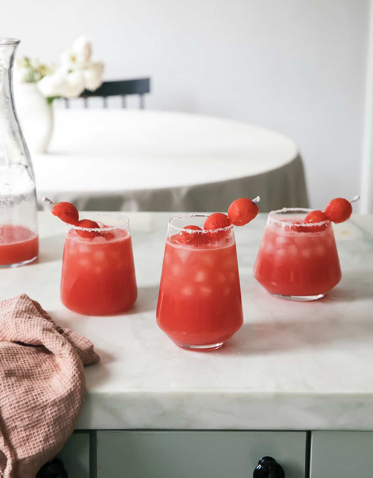 a group of glasses with red liquid and fruit on them