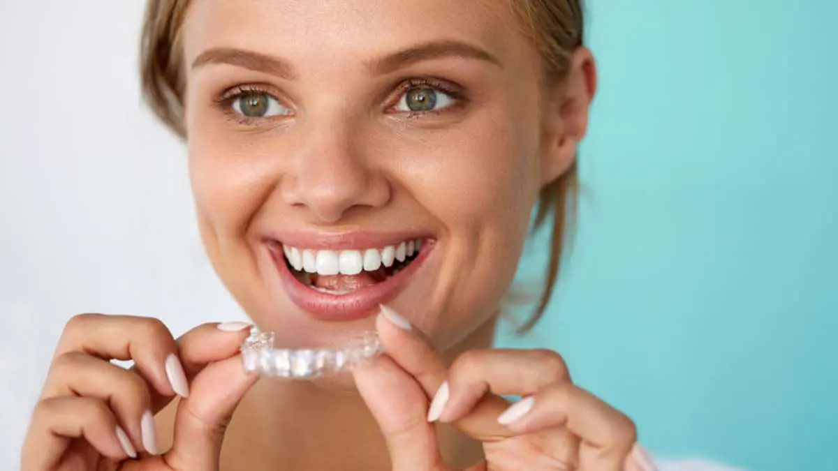 a woman smiling holding a clear plastic brace