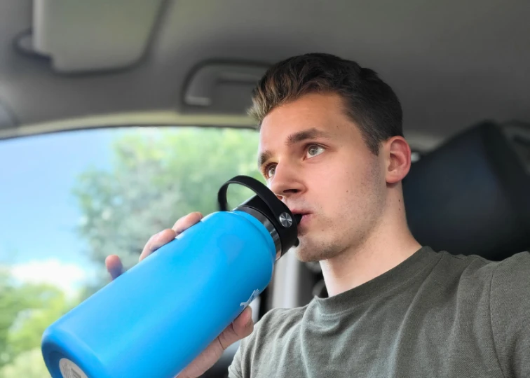 a man drinking from a blue water bottle