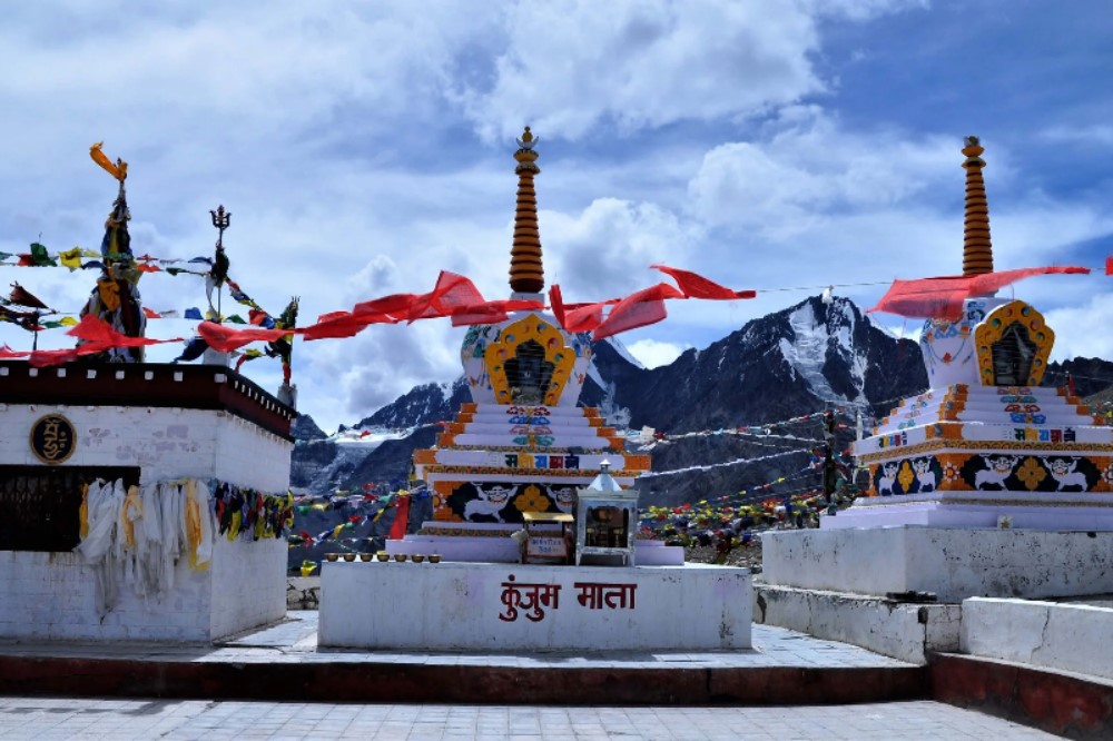 a small shrine with flags and mountains in the background