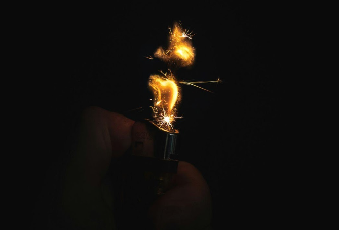 a hand holding a lighter with sparks coming out of it