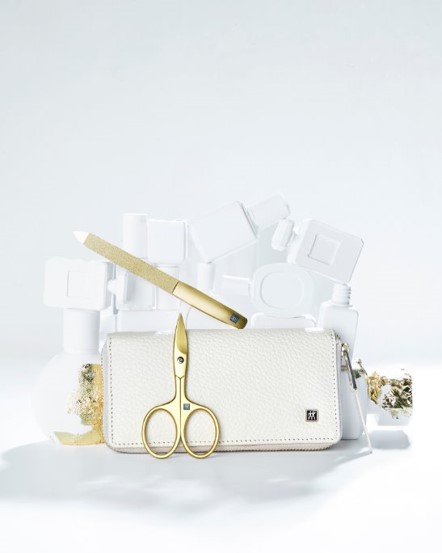 a white purse with a gold scissors and nail file