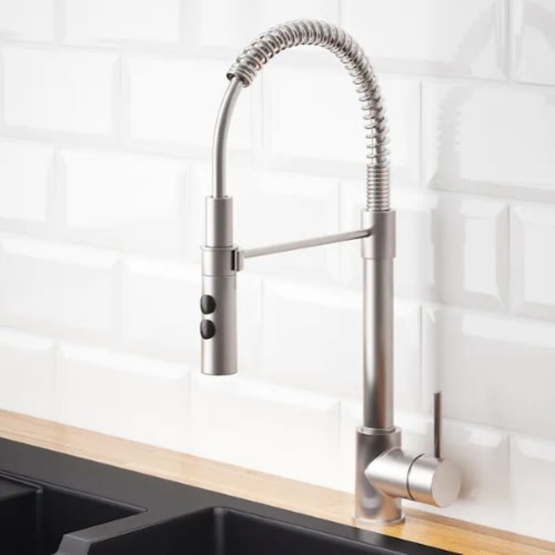 a silver faucet on a white tile wall