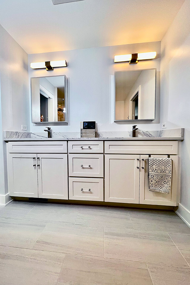a bathroom with white cabinets and mirrors