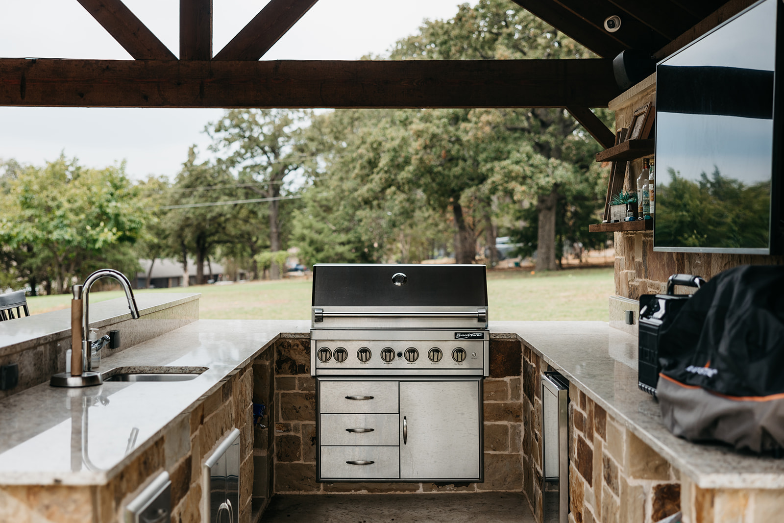 a outdoor kitchen with a grill and a stone wall
