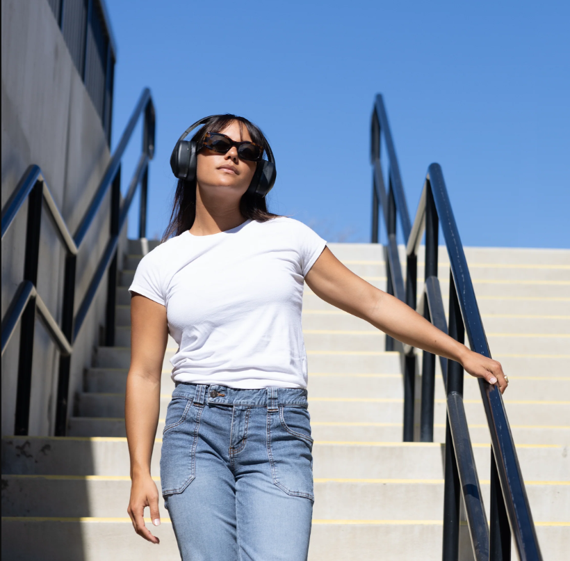 a woman wearing headphones and standing on stairs