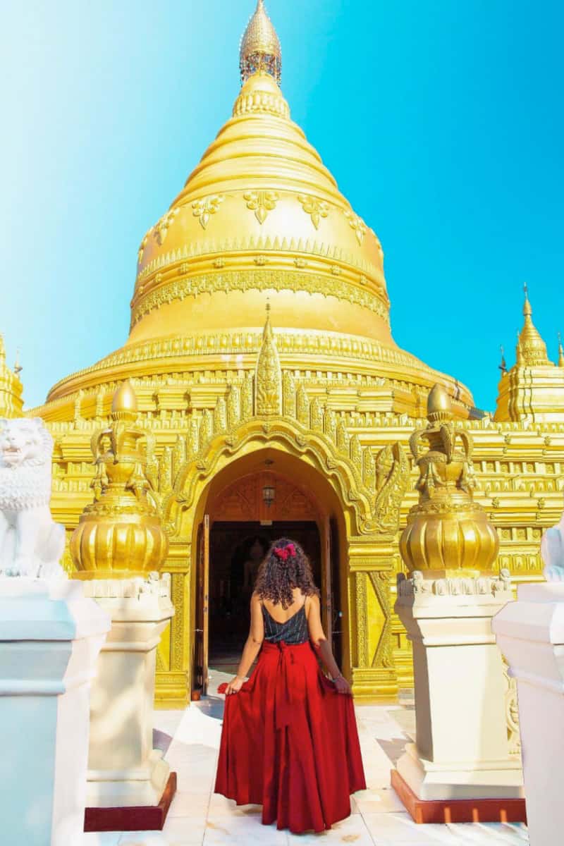 a woman in red dress standing in front of a gold building