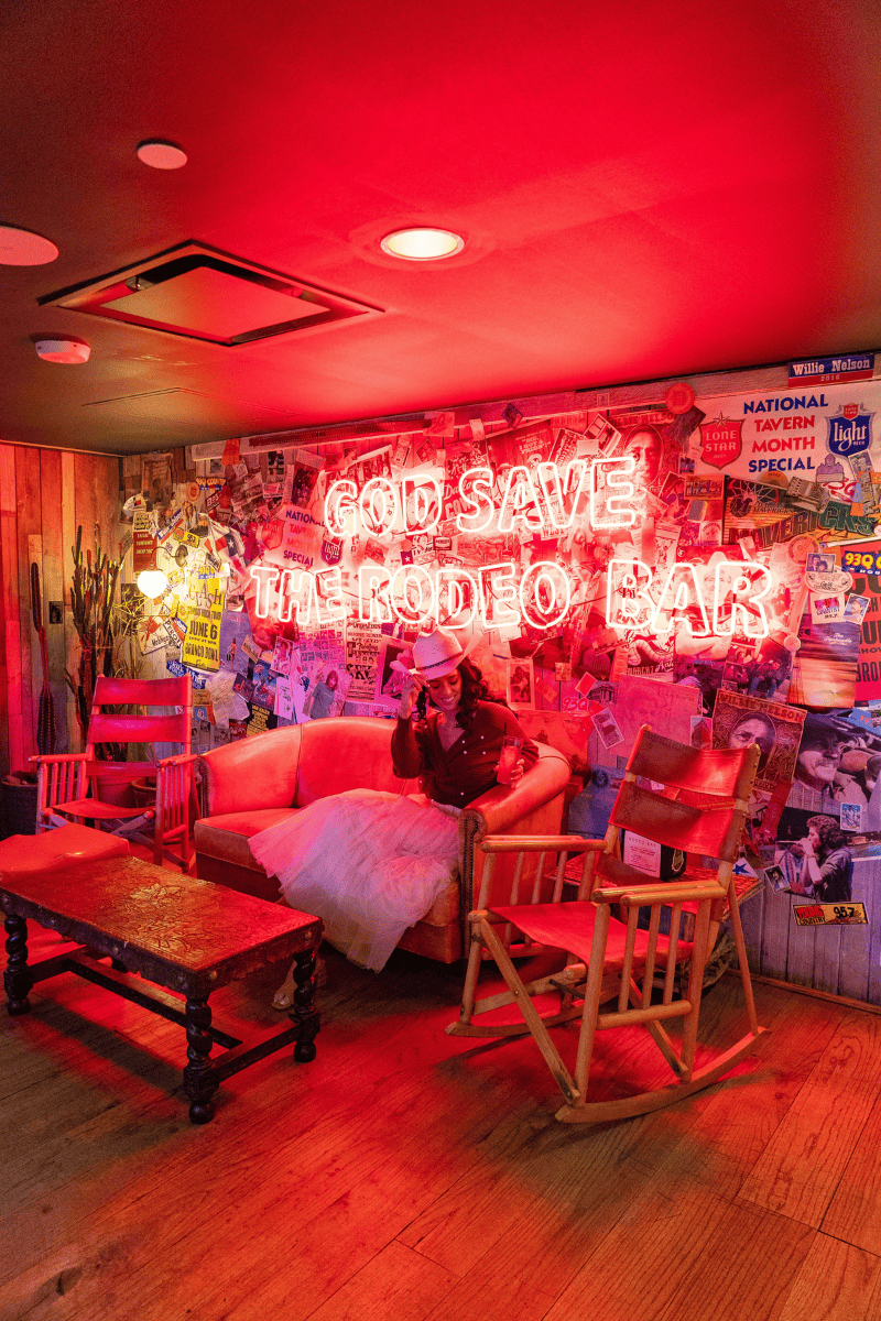 a person sitting on a couch in a room with a red neon sign