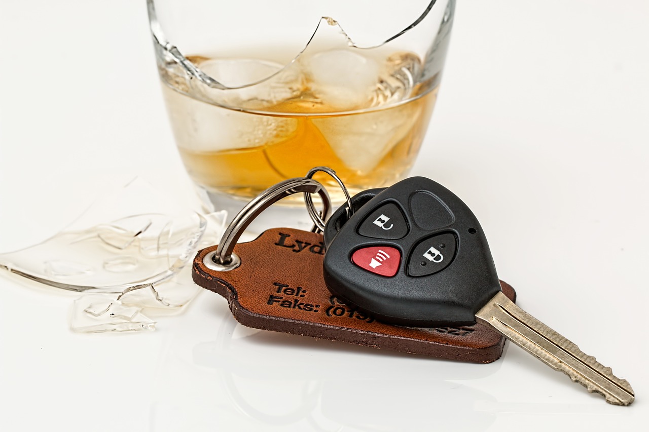 a car key on a keychain next to a glass of alcohol