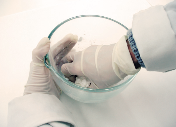 a person wearing gloves holding a bowl of white powder