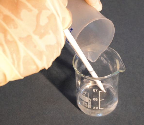 a person pouring liquid into a beaker