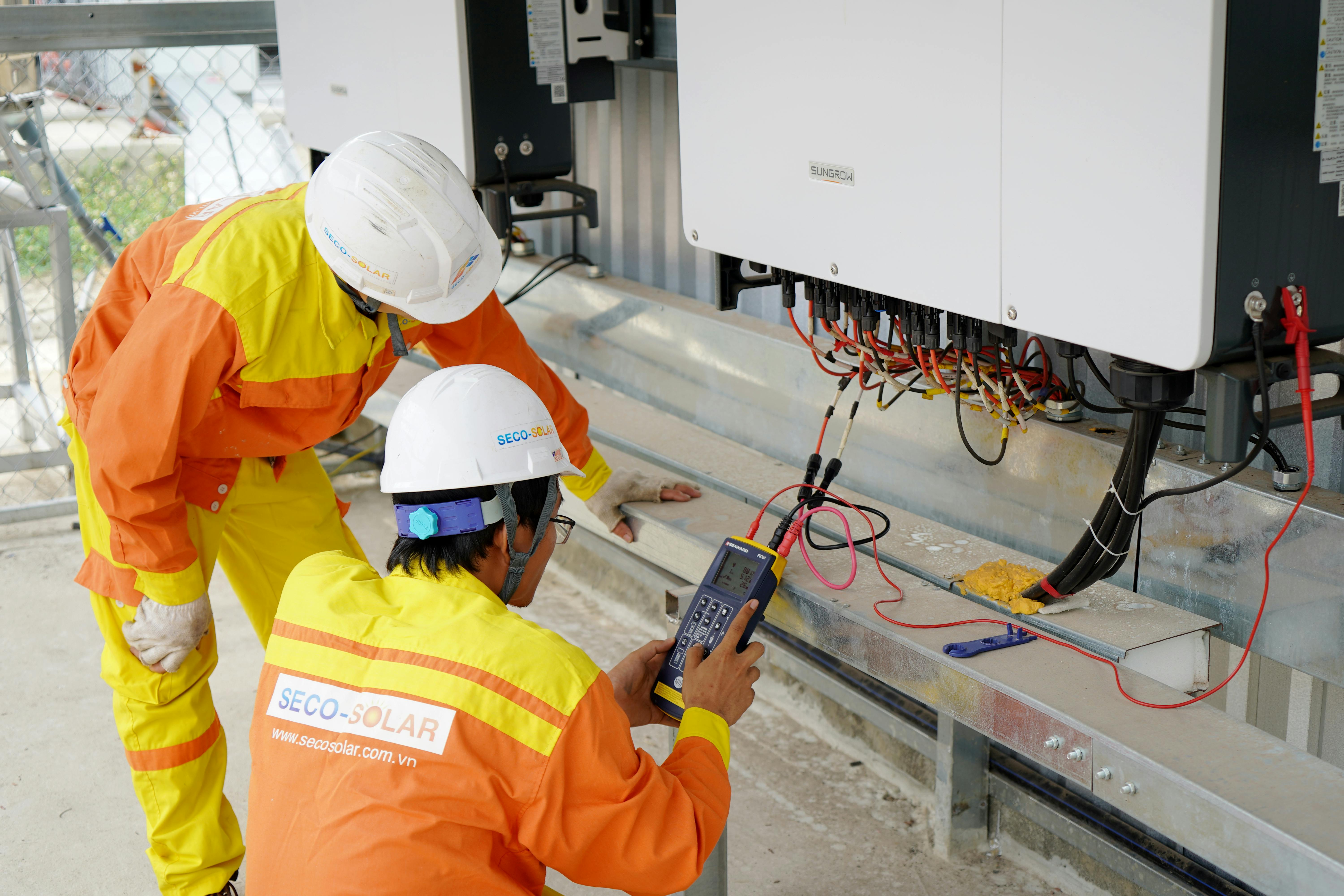 men wearing helmets and white helmets using a multimeter