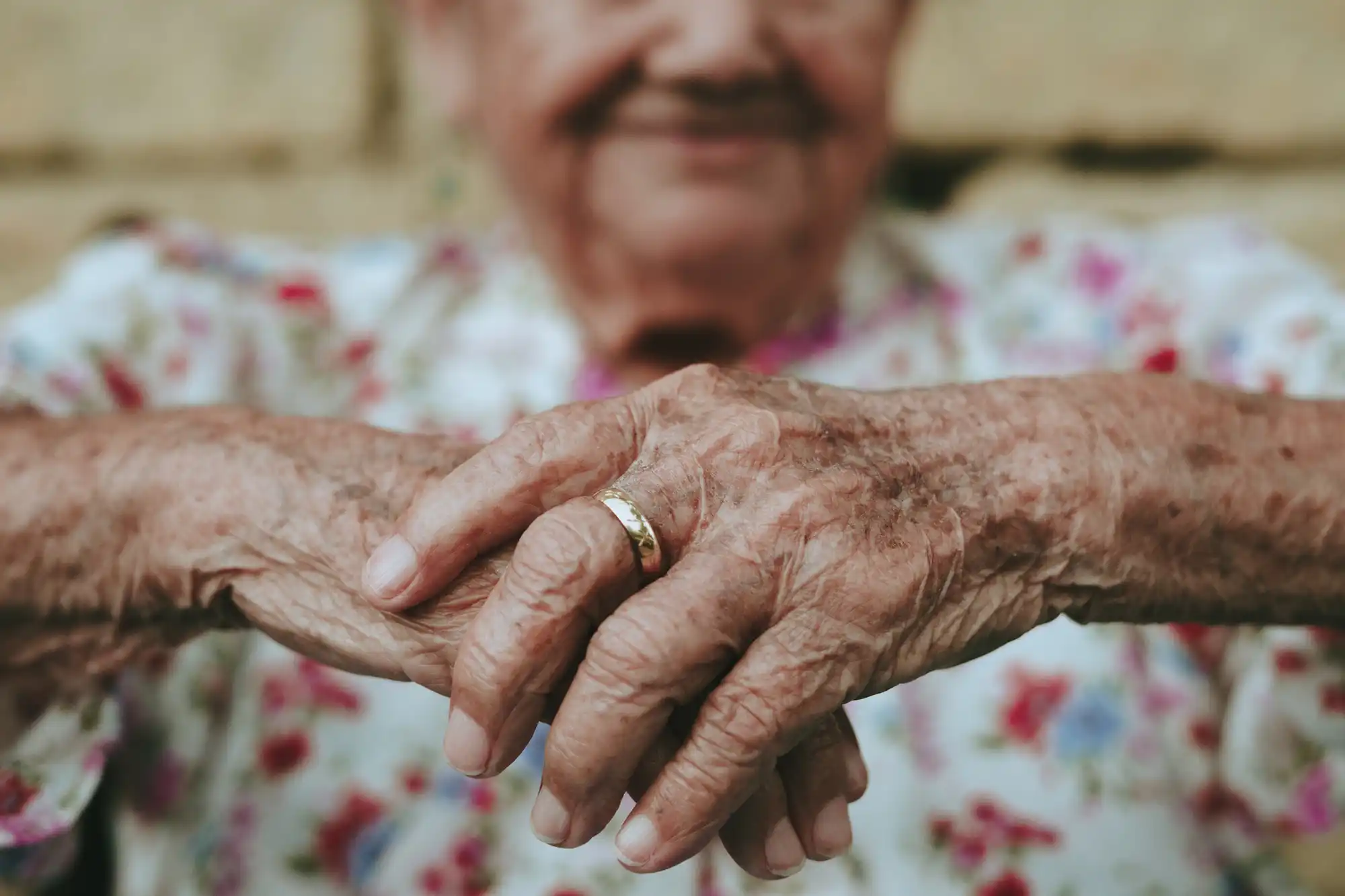 an old woman holding hands with a gold ring