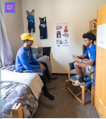 a man sitting on a bed and talking to another man