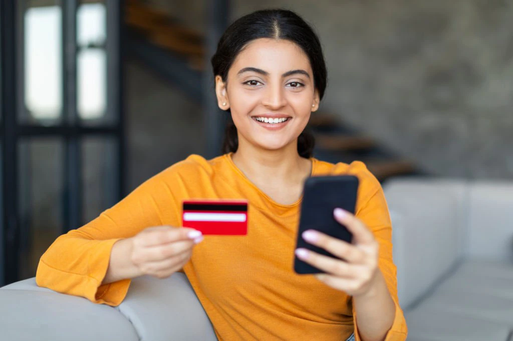 a woman holding a phone and a credit card