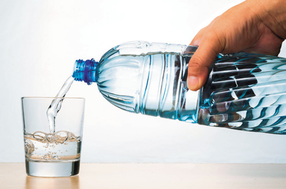 a hand pouring water into a glass