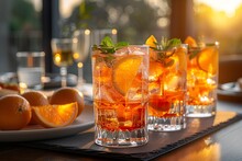 a group of glasses with oranges and ice on a table