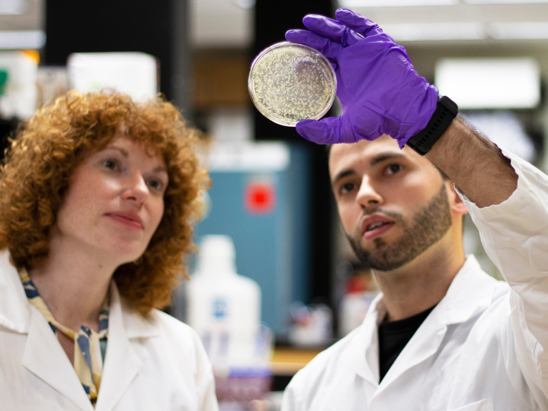 a man and woman in lab coats holding a petri dish