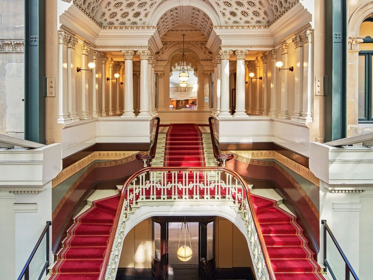 a staircase with red carpet and white columns