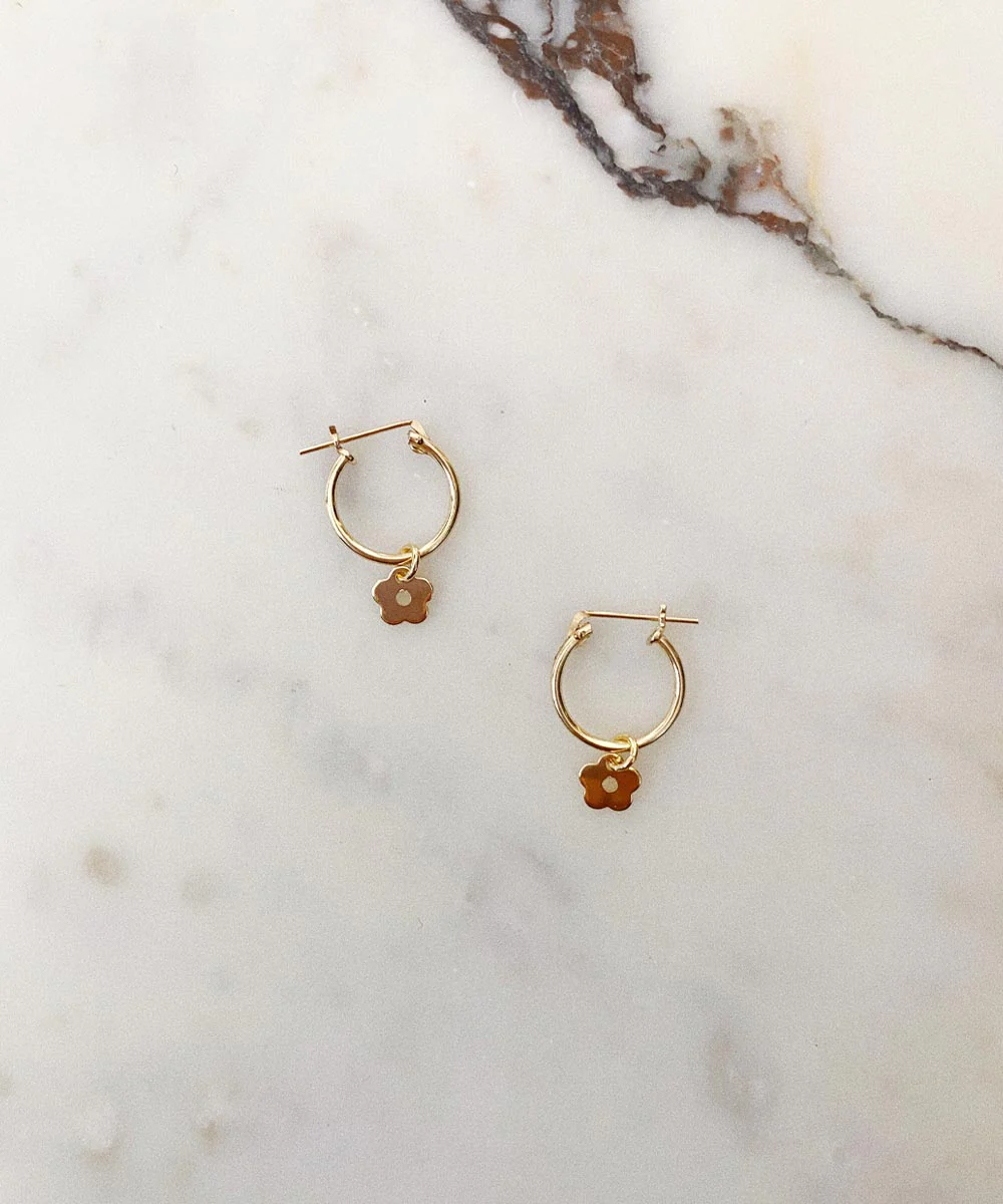 a pair of gold hoop earrings with flowers on a marble surface