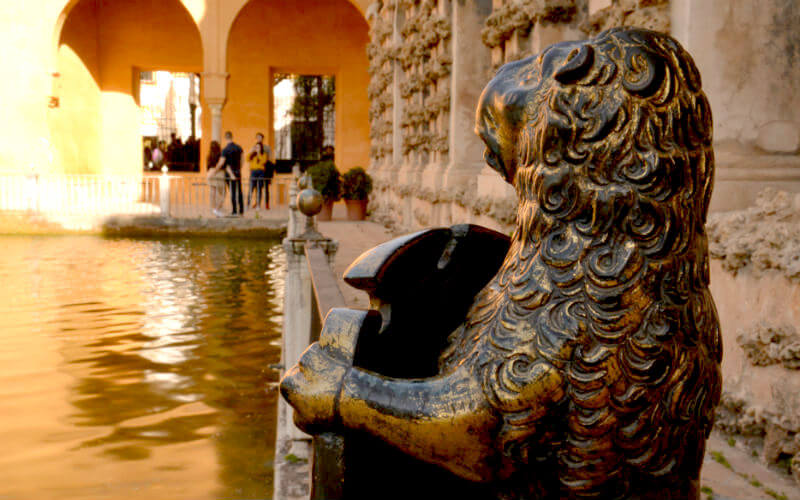 a statue of a lion next to a pond