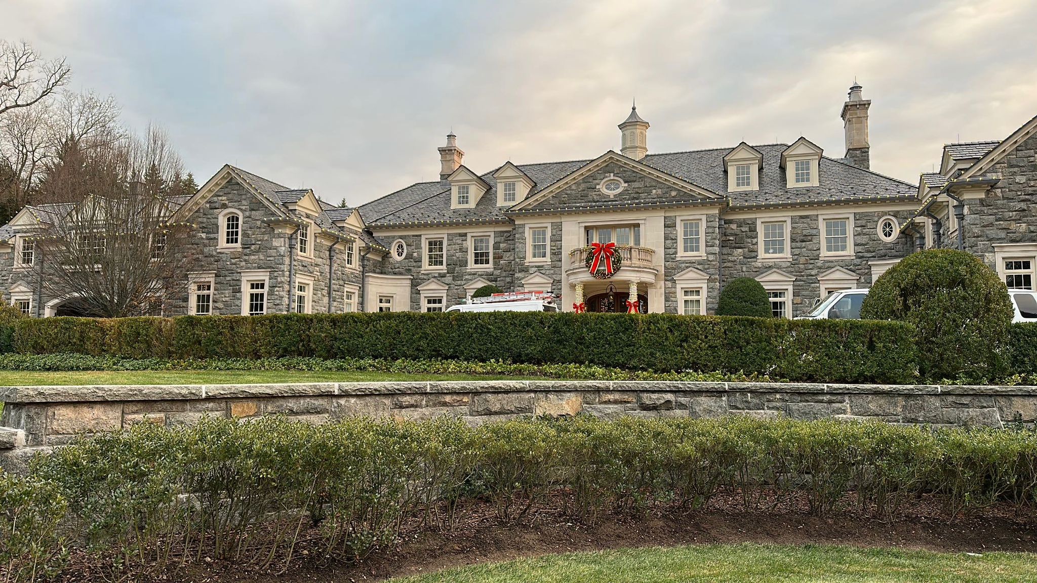 a large stone house with a large lawn and a large stone wall