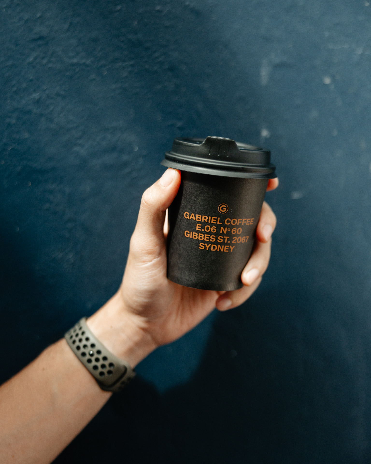 a hand holding a black coffee cup