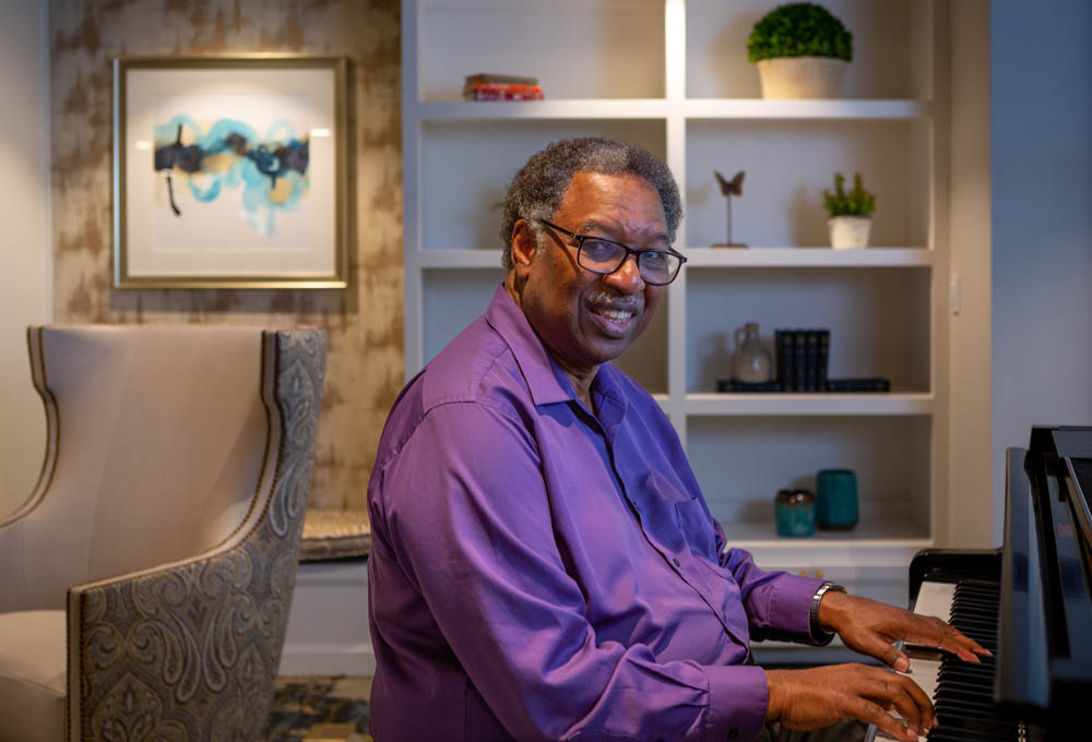 a man in a purple shirt playing a piano