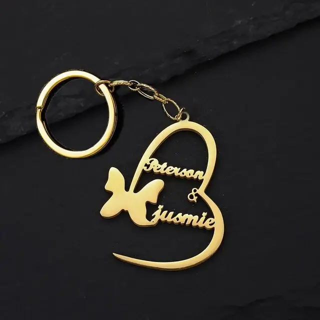 a gold heart keychain with a butterfly and a butterfly on a black surface
