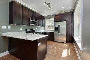 a kitchen with dark cabinets and a stainless steel refrigerator