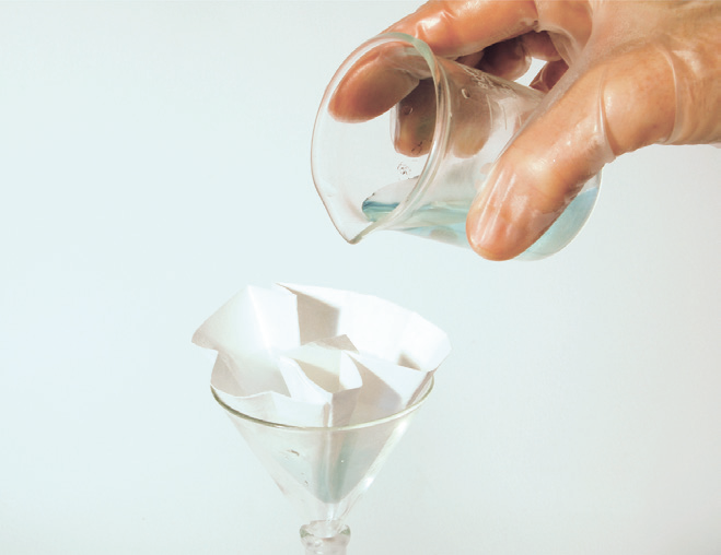 a hand pouring liquid into a glass