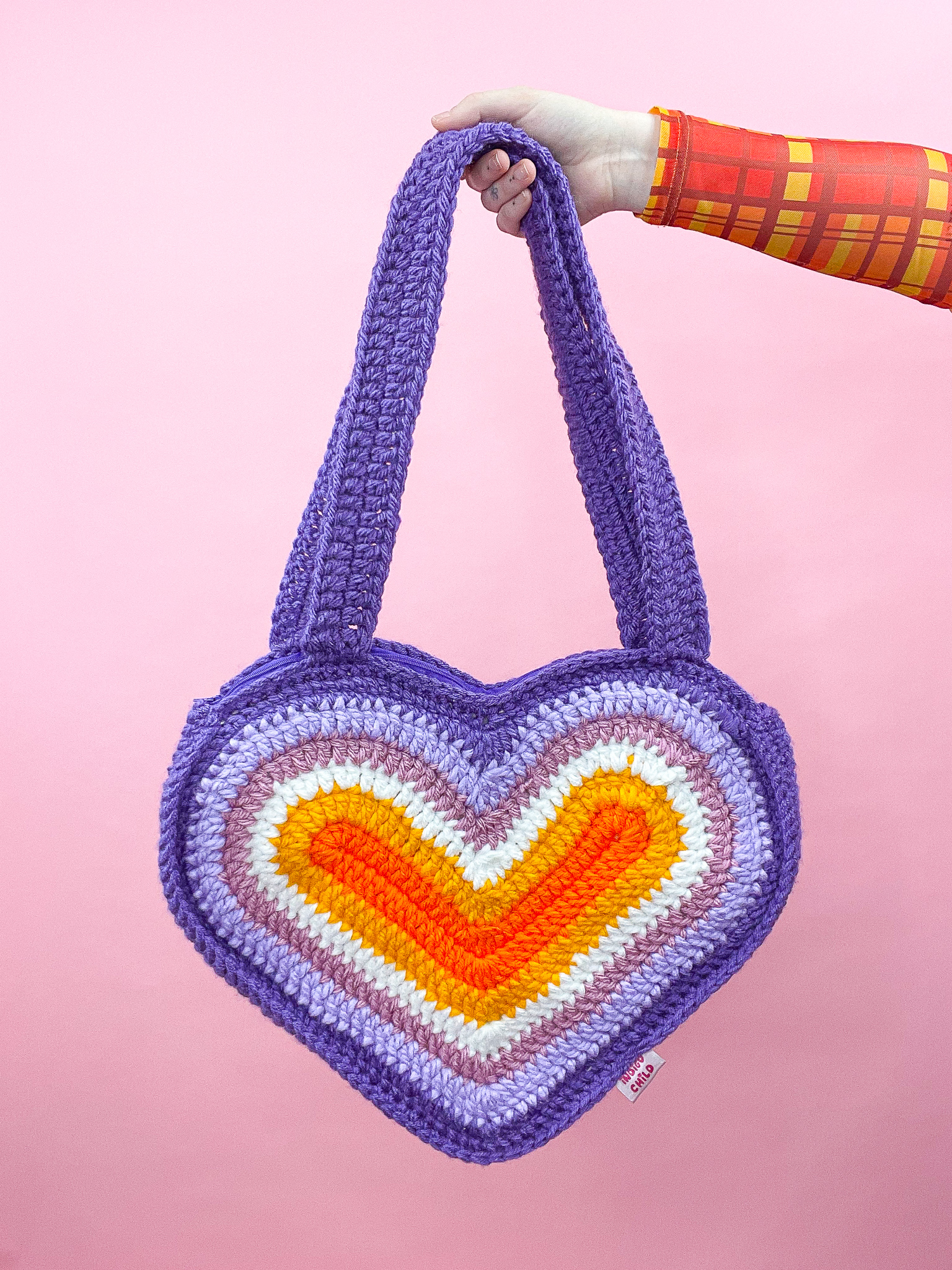 a hand holding a knitted heart shaped bag