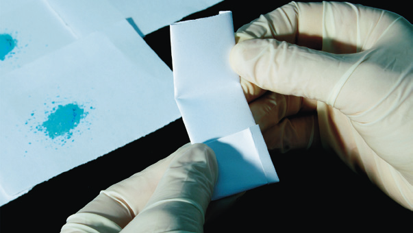 hands wearing gloves holding a piece of paper