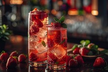 two glasses of red liquid with strawberries and ice