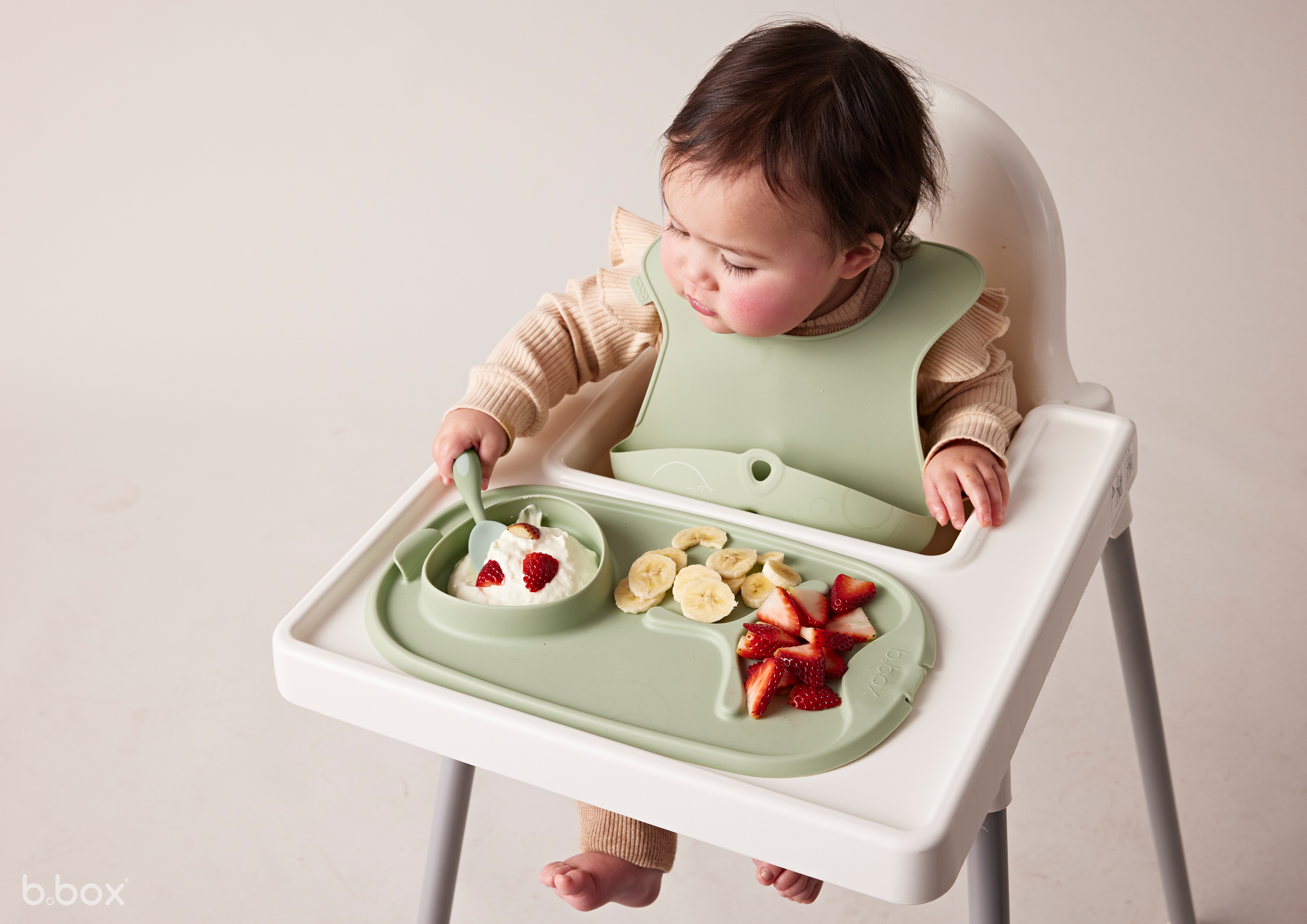 a baby sitting in a highchair eating fruit