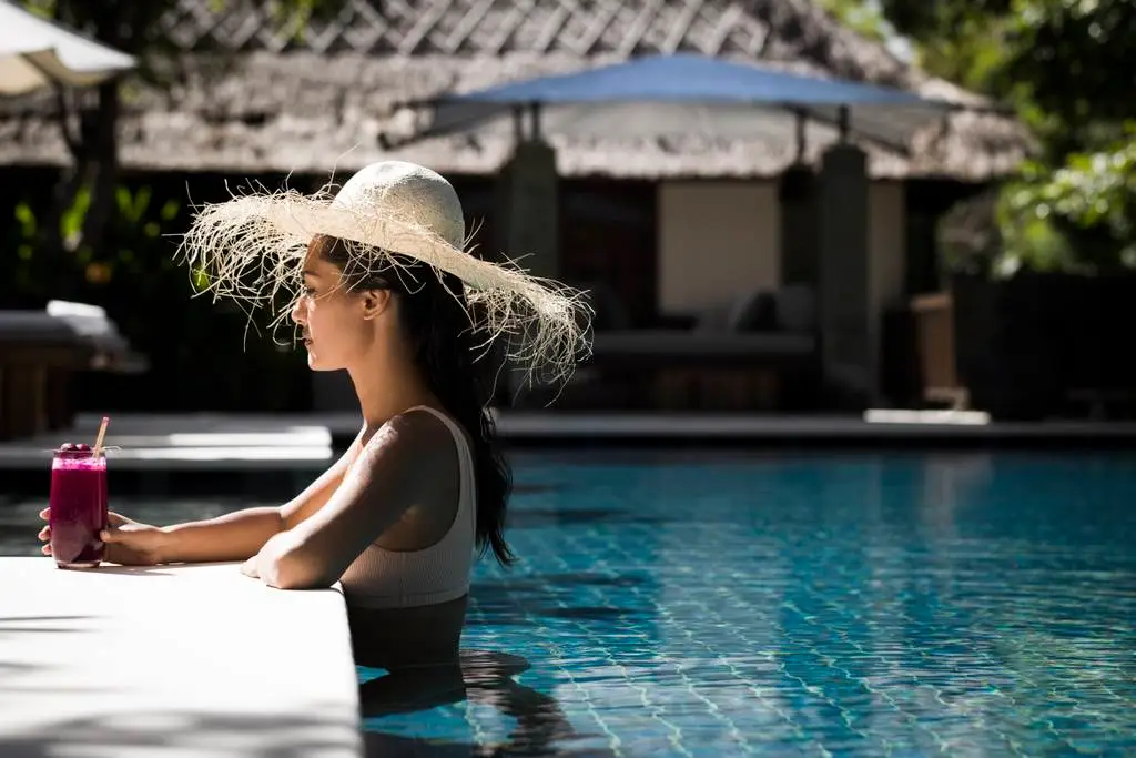 a woman in a hat leaning on a pool