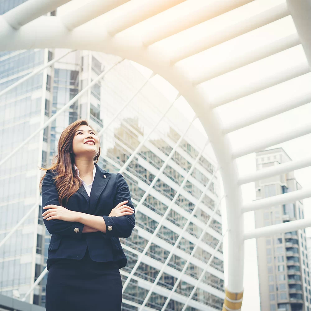 a woman standing under a white structure with buildings in the background