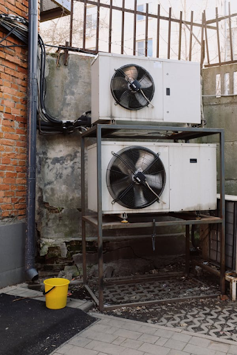 two white air conditioning units on a metal stand