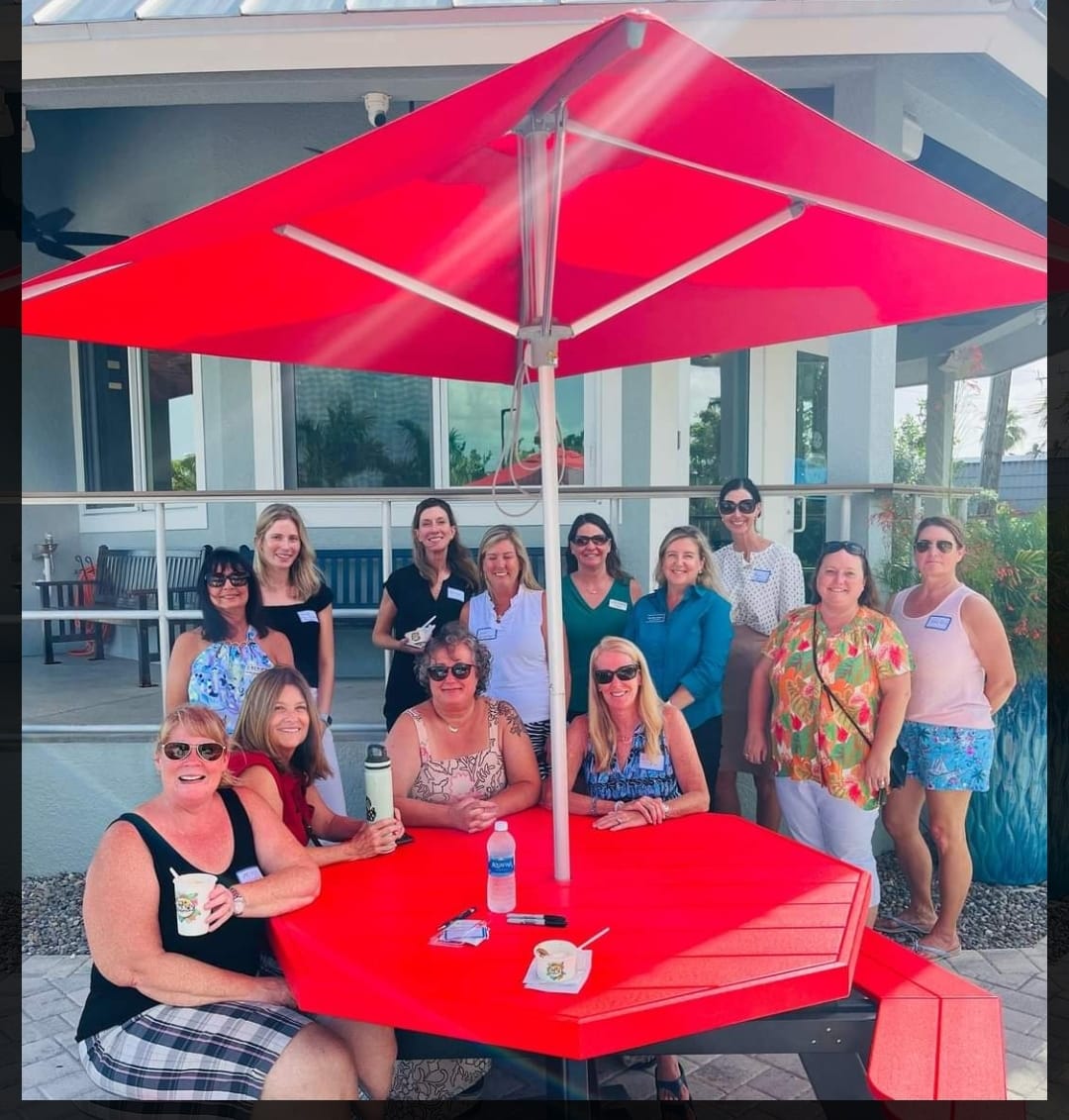 a group of women posing for a photo under a red umbrella