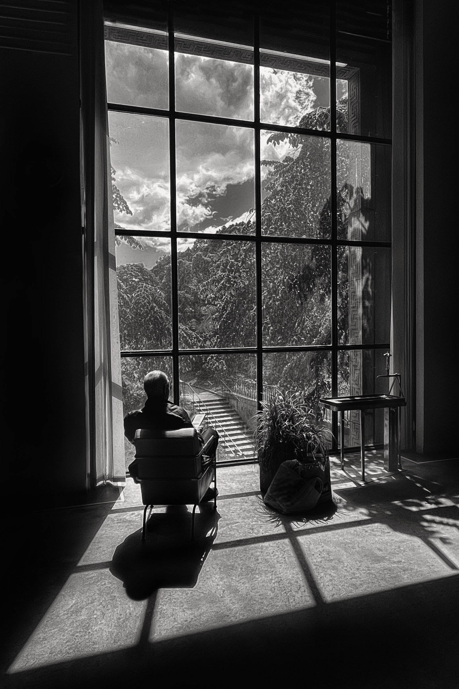 a man sitting in a chair looking out a large window