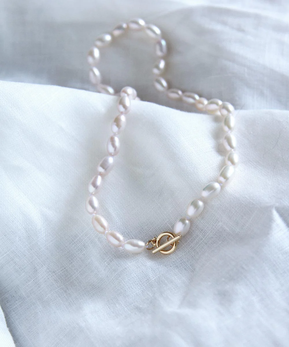 a pearl necklace on a white cloth