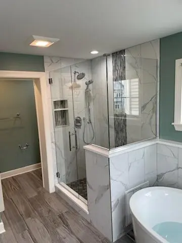 a bathroom with a glass shower and a tub