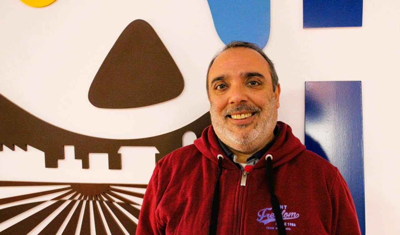 a man smiling in front of a wall with a picture of a castle