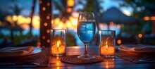 a glass of blue liquid and candles on a table