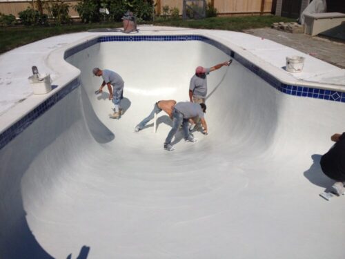 a group of men painting a pool