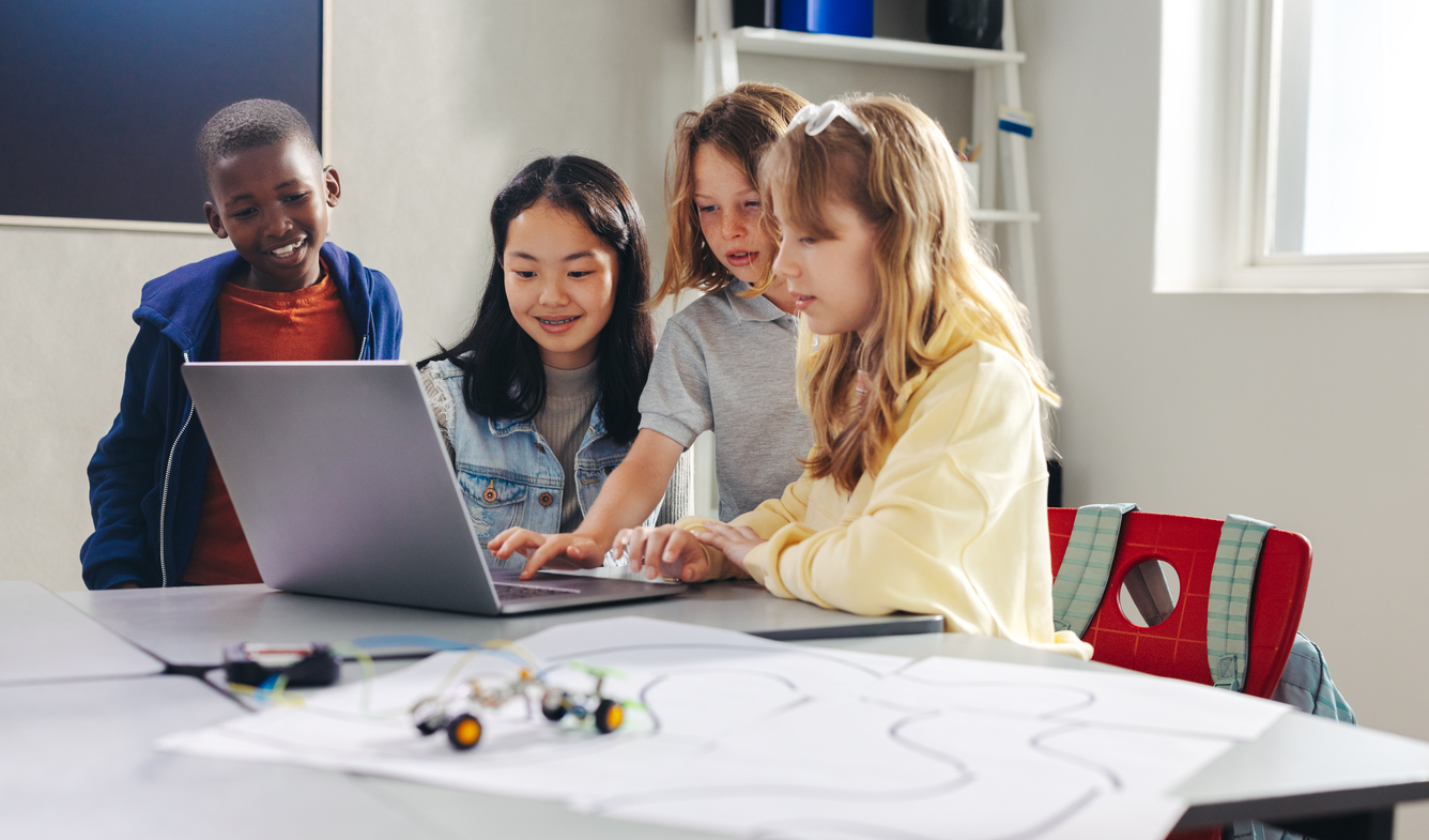 a group of kids looking at a laptop