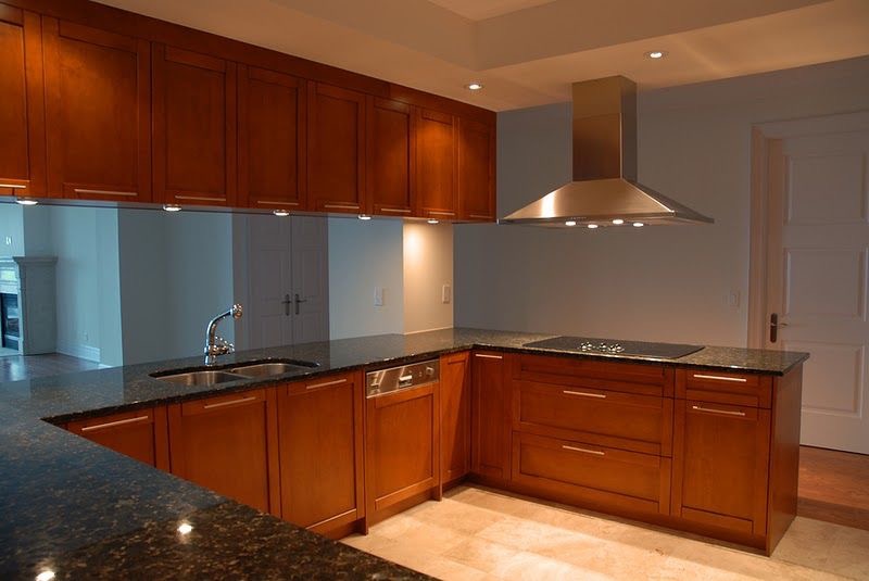 a kitchen with dark wood cabinets and marble counter tops