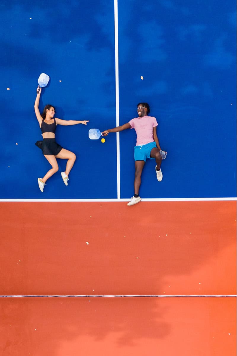 a man and woman lying on a tennis court