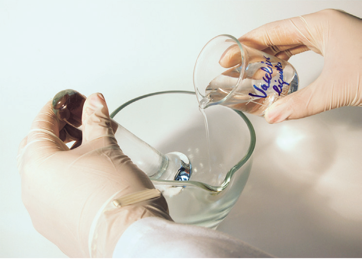 hands holding a beaker and a glass container